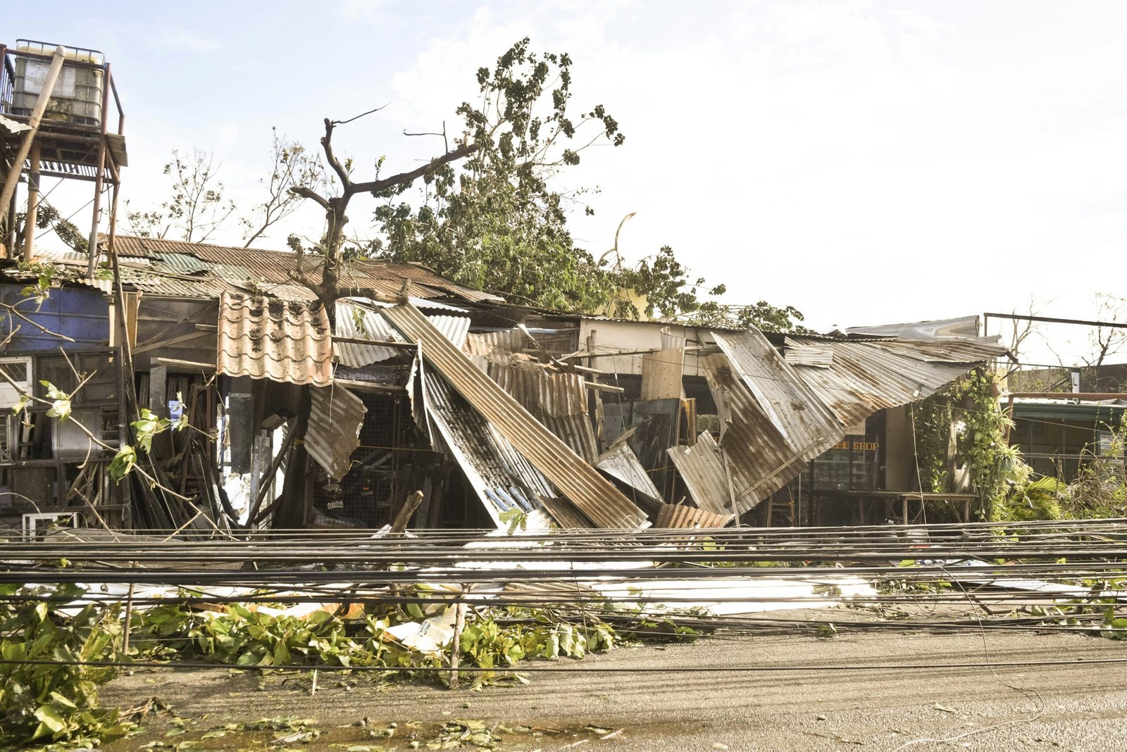Damaged houses with collapsed corrugated metal roofs and debris after typhoon in Philippine community